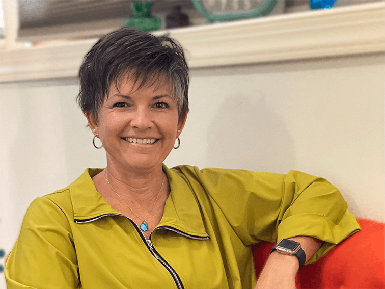 Julie sitting on a red couch wearing a green jacket